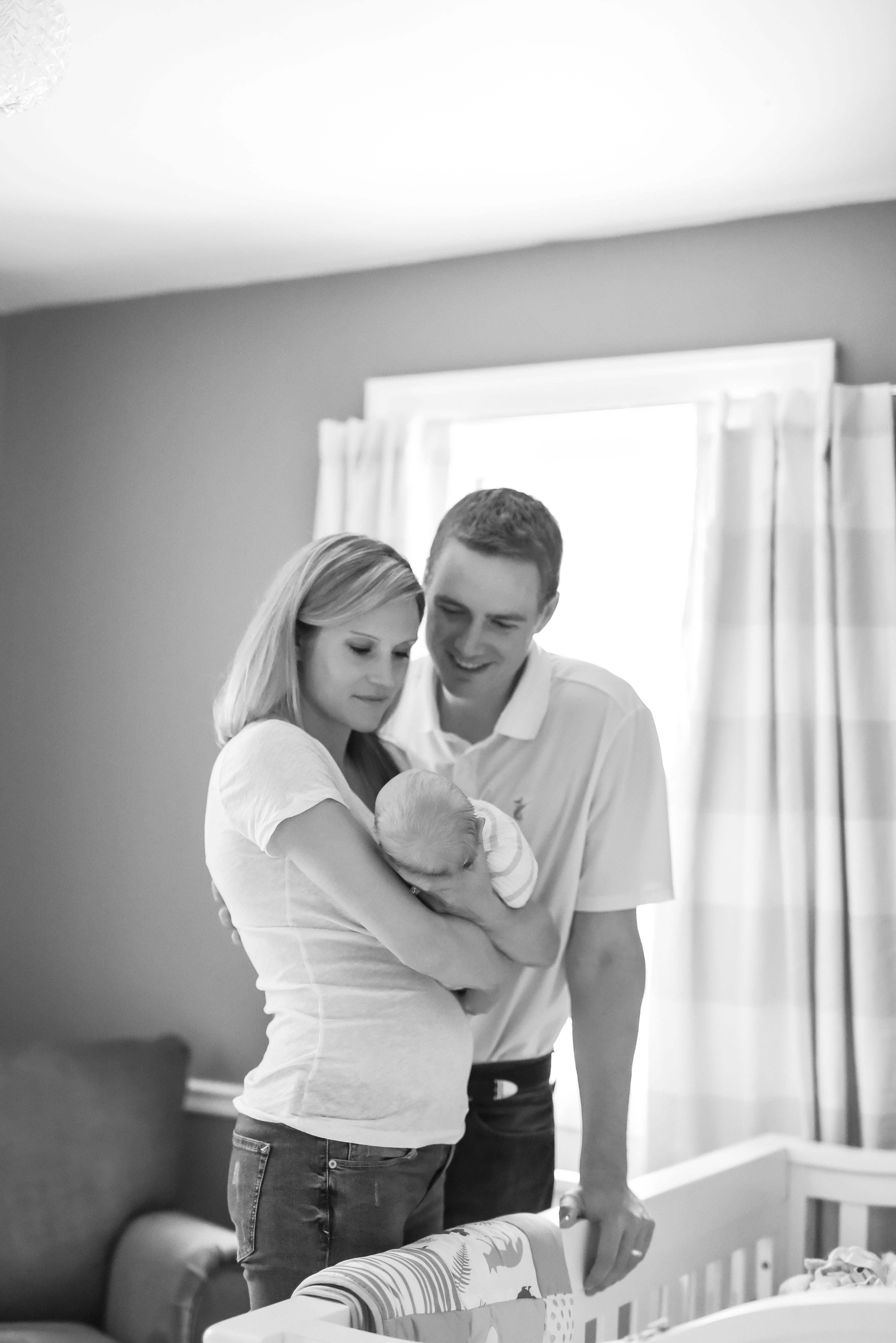 a new mom holds her newborn while dad looks on 