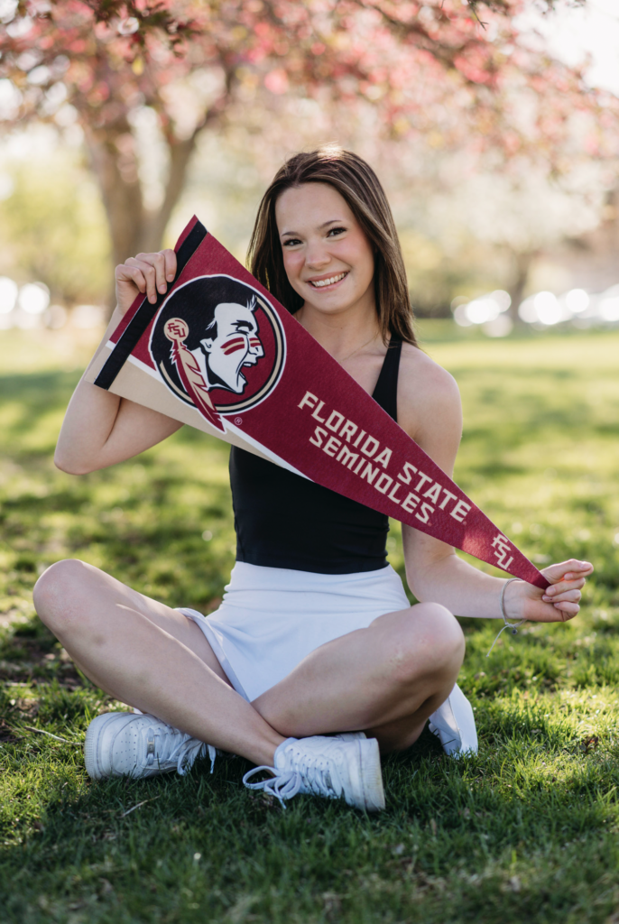 a senior girl poses with a florida state banner