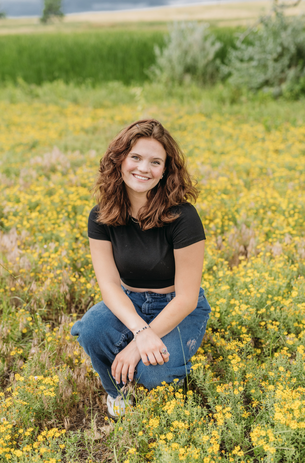 a senior girl poses in a denver field of yellow flowers