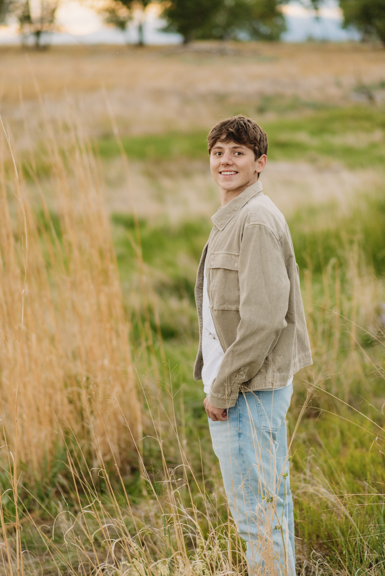 a senior boy looks at the camera while posing in a field